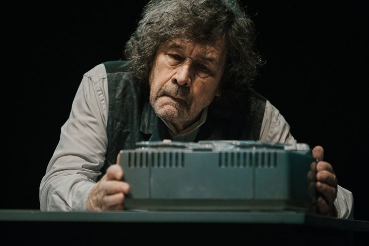 Stephen Rea hunched over a tape recorder looking sad