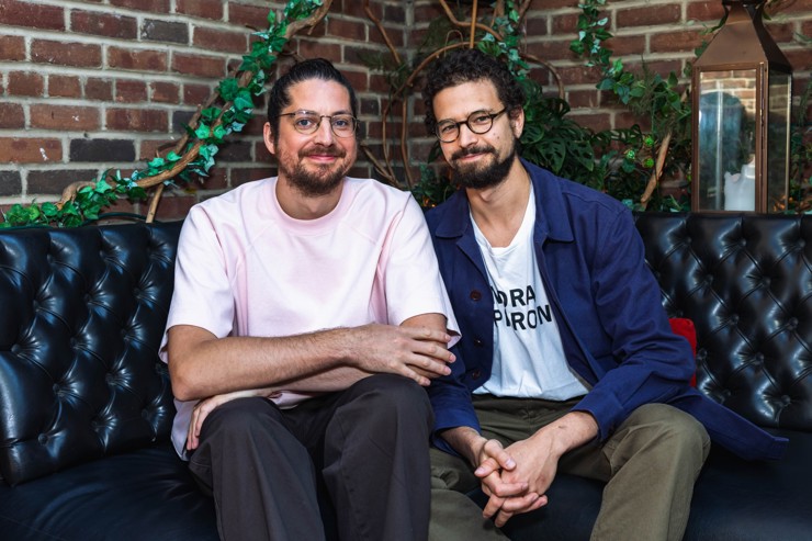 The two writers sitting together on a sofa and smiling