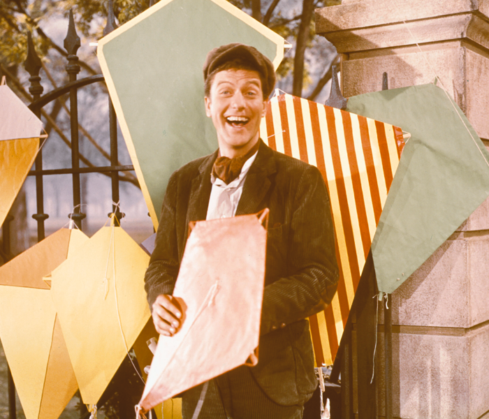 A smiling Dick Van Dyke surrounded by kites on the set of the movie Mary Poppins 