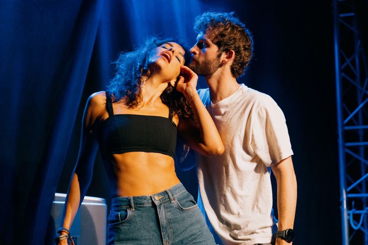 A woman throwing her head back next to a man about to kiss her