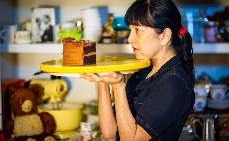 A woman holding a tray with a big piece of chocolate cake