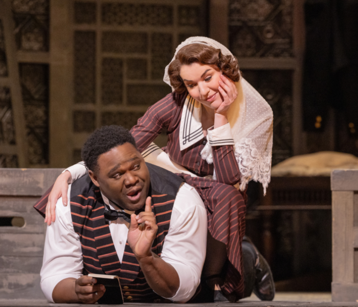 A man resting on the floor talking to a woman sitting on a bench 