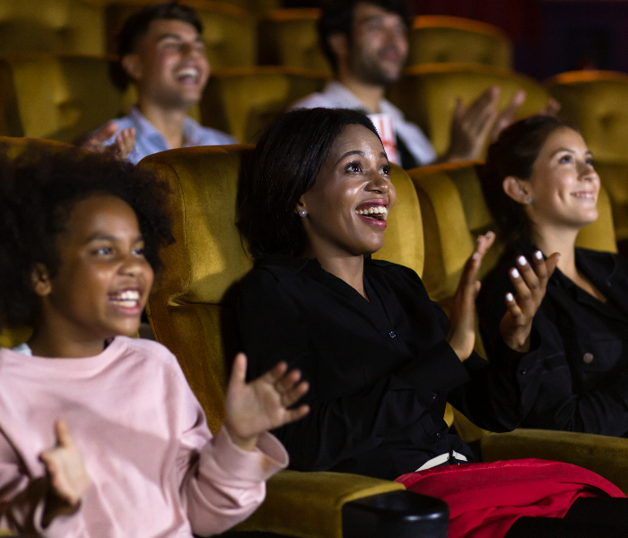 A diverse audience enjoying theatre and clapping their hands; Shutterstock