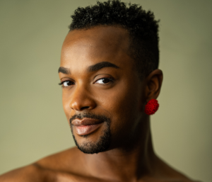 A close-up of J. Harrison Ghee with a red earring and a slight smile