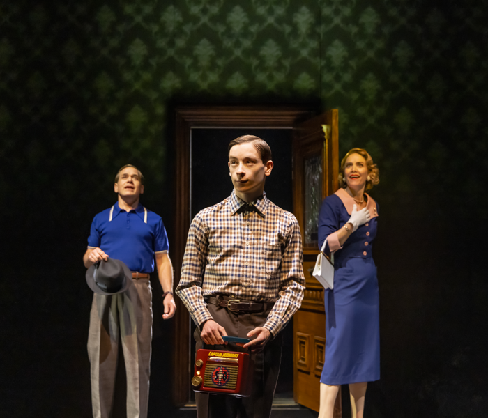 An awkward teen standing in front of his parents in retro clothing