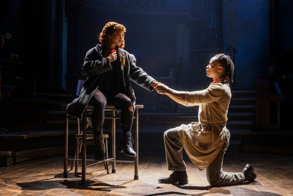 A woman sitting on a table and a man on his knees holding her hand