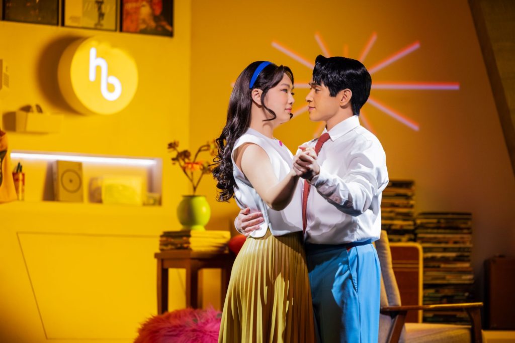 A woman and a man dancing against a yellow background
