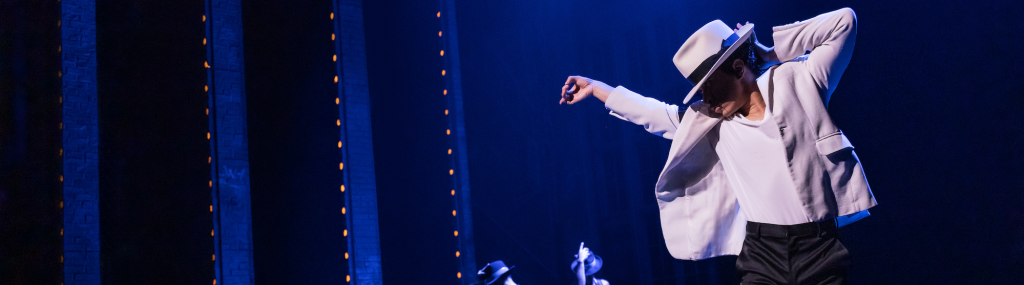 A performer as Michael Jackson in a white suit posing