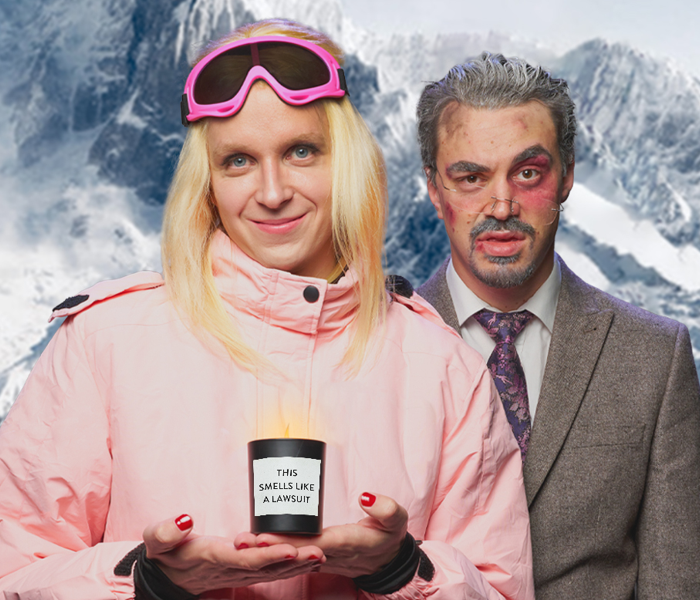 A performer playing Gwyneth Paltrow in pink ski gear next to a man in a gray suit with a black eye
