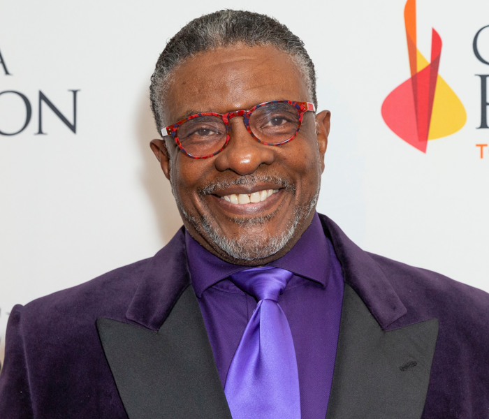A close-up image of Keith David smiling with a purple tie