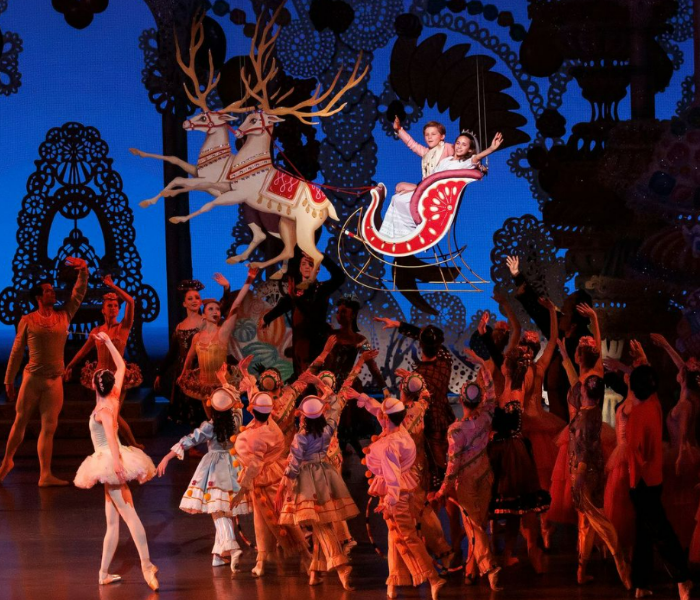 An ensemble of Nutcracker dancers waving goodbye to Clara and the Nutcracker who are in an airborne sleigh
