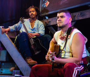 Two men looking pensive one with a guitar