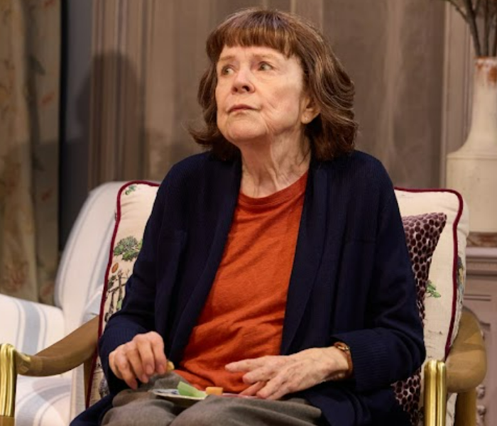 An older woman sitting in a chair looking pensive