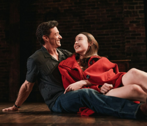 A man reclining on the floor with a younger woman in red in his lap