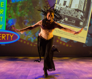 A woman tap-dancing with her dreadlocks flying