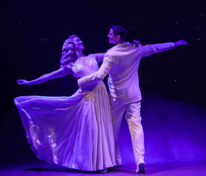 A woman and a man dancing together under a purple light