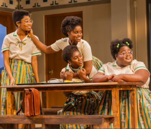 Four young women gathered around a table looking excited