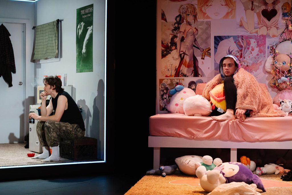 A man siting on a cube in a gray room looking sad juxtaposed with a person in a very pink room also looking sad
