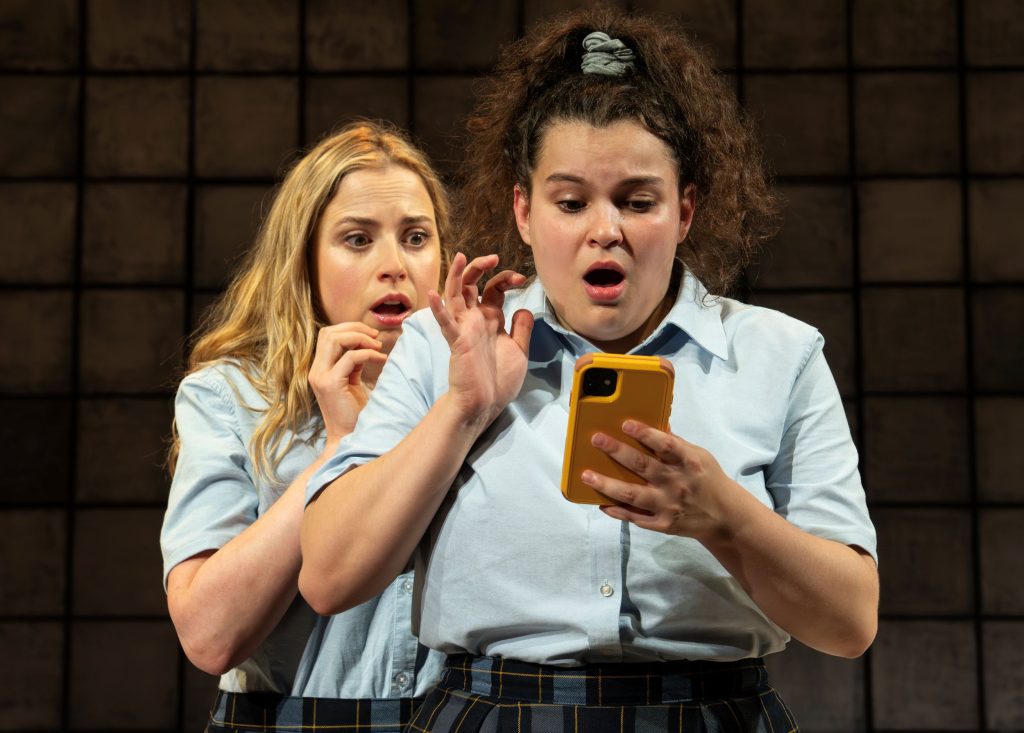 Two teenage girls looking at a cell phone in shock