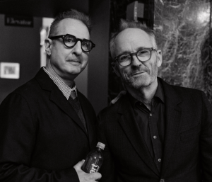 A black-and-white photo of two men posing together and smiling slightly